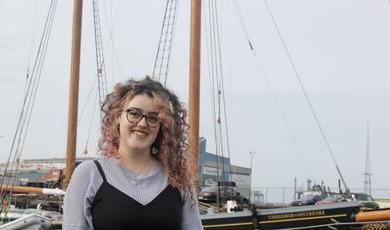 Carolyn King stands in front of an old whaling ship.